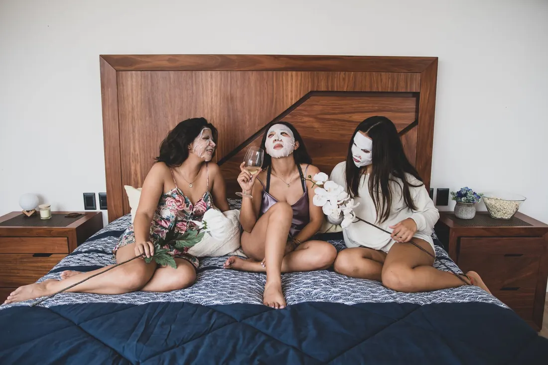 Friends in face masks relaxing on a bed