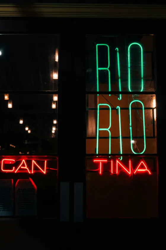 A red neon cantina sign at night
