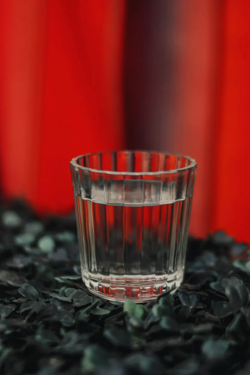 A glass of mezcal on a red background