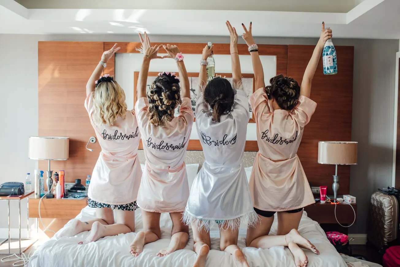 Bridesmaids in robes celebrating on a bed